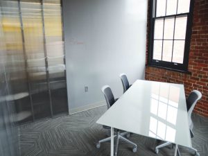 An empty office with a table and a whiteboard, representing space to check out while you prepare your office for moving day.